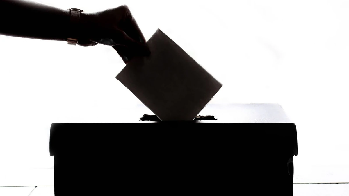 Silhueta de mão depositando cédula de votação em uma urna, símbolo da democracia, tema da reunião do TSE sobre proibição de deepfakes nas eleições de 2026